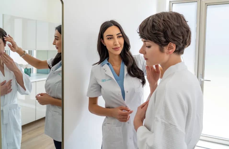 Specialist van RB Clinics bespreekt de huid van een cliënt voor de spiegel