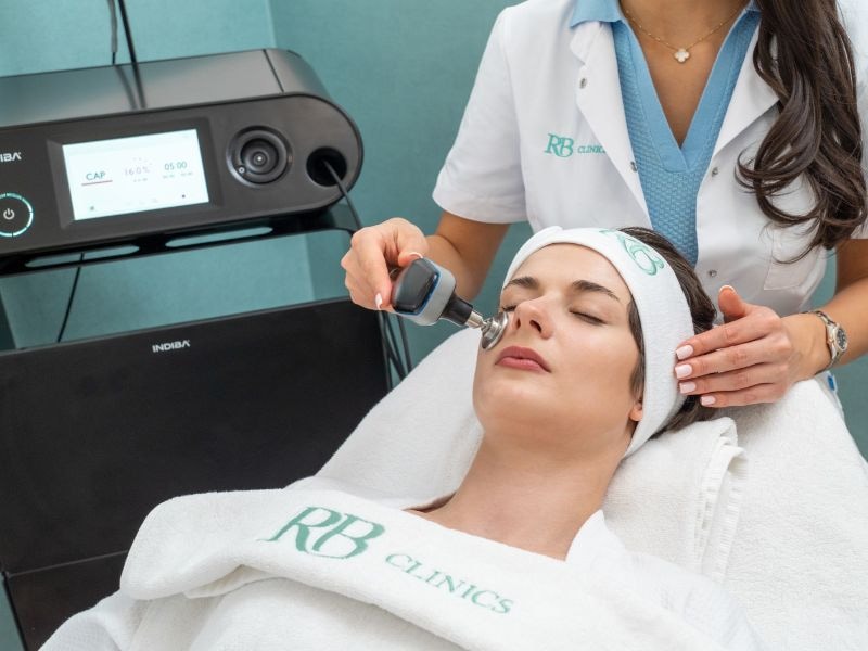 Specialist van RB Clinics behandelt het gezicht met de Indiba applicator, met de Indiba Edna Pro Max ernaast