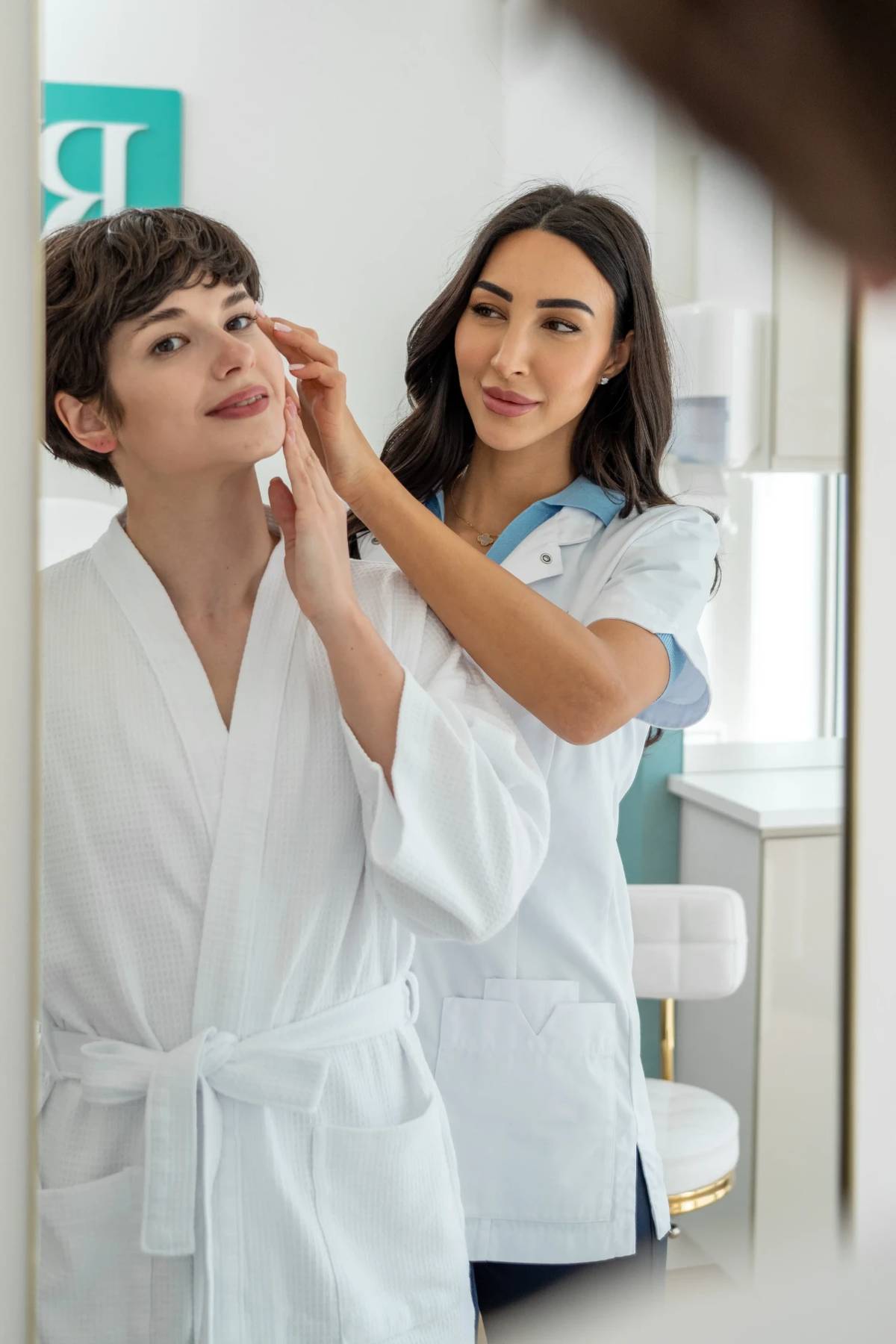 Specialist beoordeelt de huid van het gezicht van een client voor de spiegel bij RB Clinics