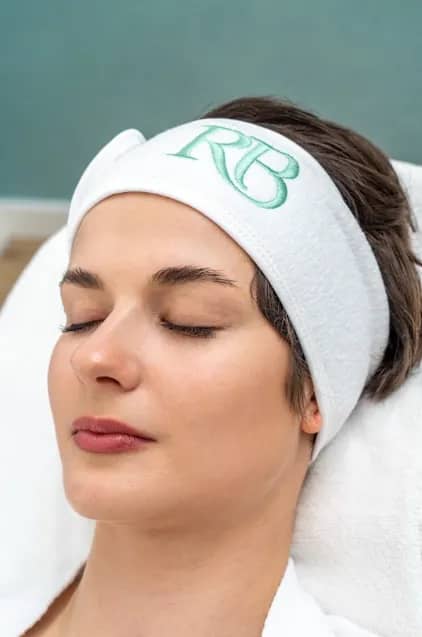 Cliënt ontspant met een RB Clinics haarband tijdens een gezichtsbehandeling