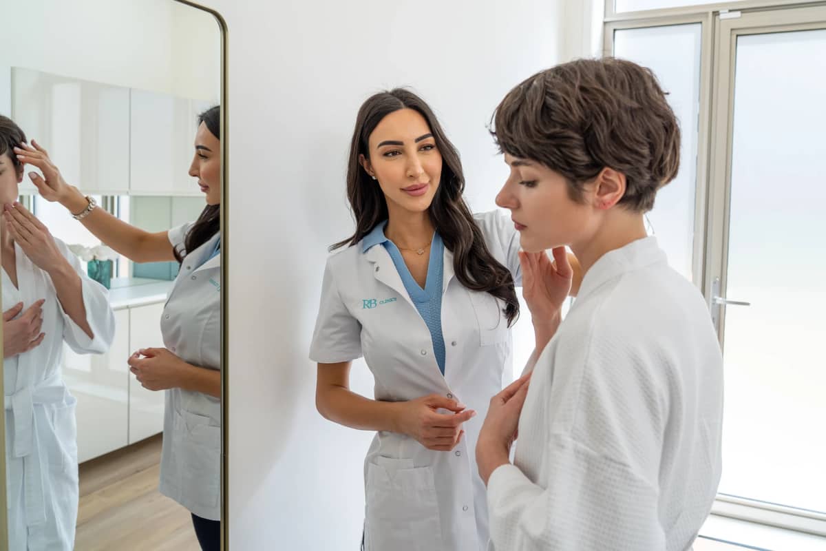 Specialist bespreekt de huid van een client voor de spiegel bij RB Clinics