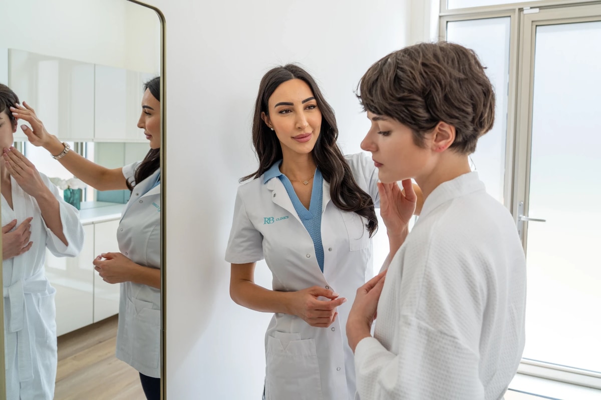 Specialist bespreekt de huid van een client voor de spiegel bij RB Clinics