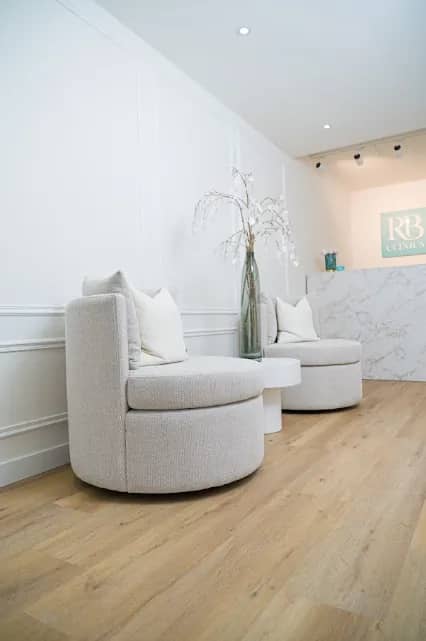 Lichte wachtruimte van RB Clinics met fauteuils en receptie op de achtergrond