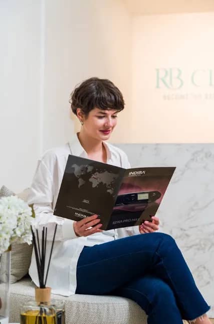 Cliënt leest een Indiba brochure in de wachtruimte van RB Clinics