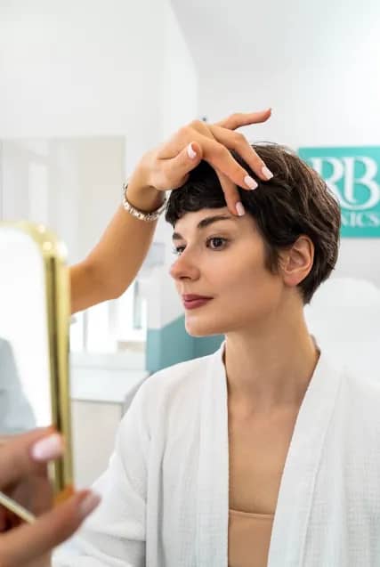 Cliënt bekijkt haar huid in de spiegel bij RB Clinics