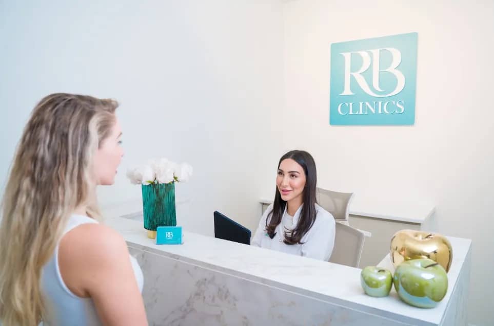 Cliënt aan de receptiebalie van RB Clinics met specialist achter de balie