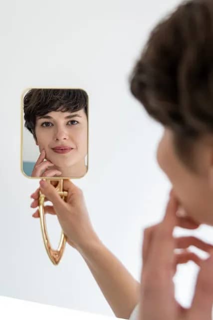 Cliënt bekijkt haar huid in een handspiegel bij RB Clinics